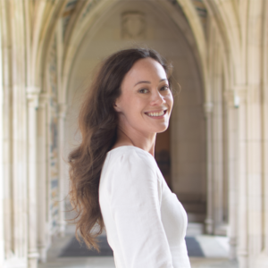 Image of Jana Soli in a white top, with a stone archway in the background