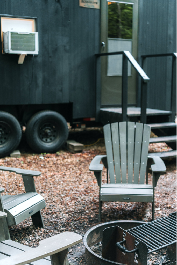 Airbnb outdoor sitting chairs and fire pit alongside a cozy tiny home