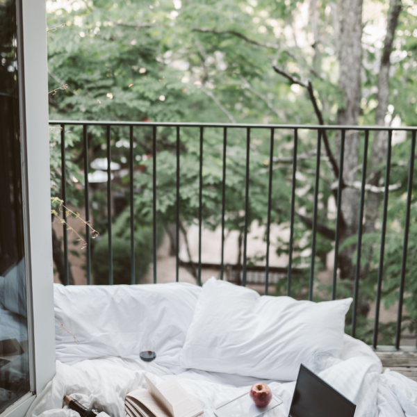 Image of bed beside open balcony door of an Airbnb. A book rests on the bedsheets.