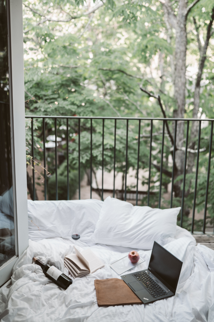 Image of bed beside open balcony door of an Airbnb. A book rests on the bedsheets.