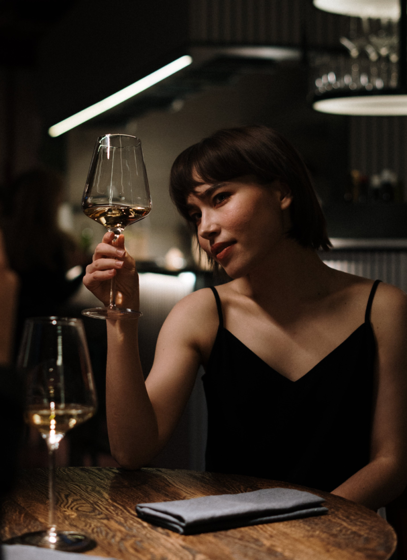 Image of woman with black hair holding wine glass in restaurant