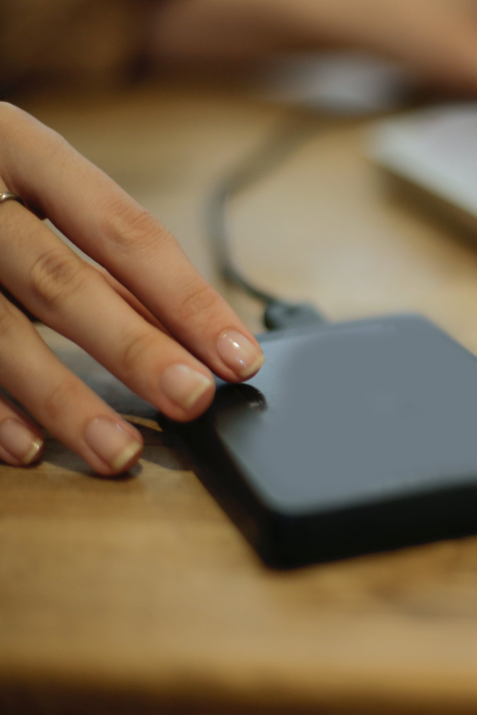 Image of portable battery charger with womans hand beside it