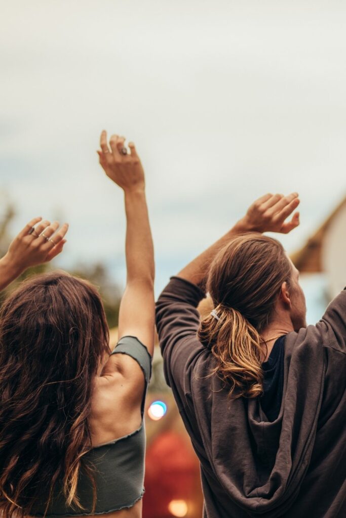 image of young woman and young man dancing with arms in the air at a music festival