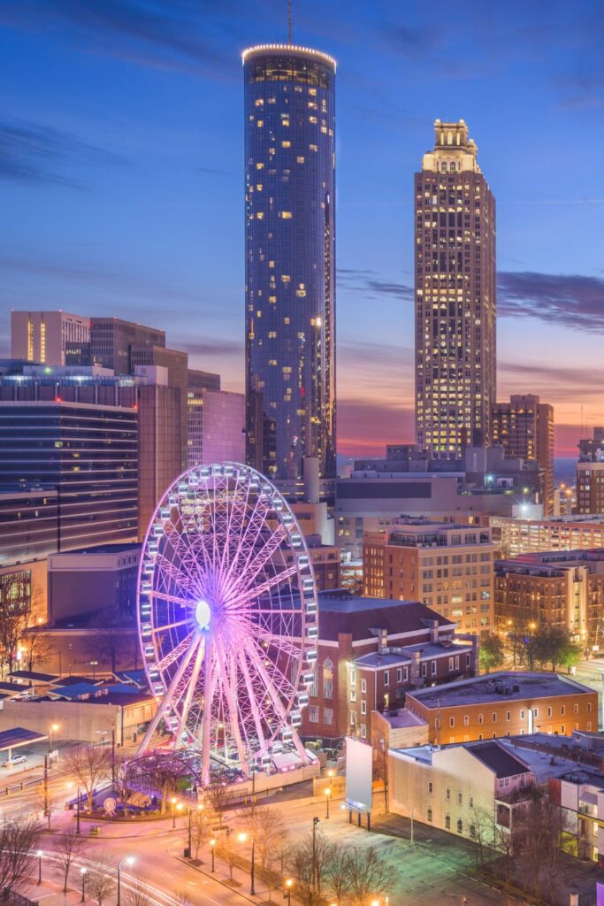 Image of Atlanta Georgia skyline at dusk with ferris wheel in foreground and high rises behind.