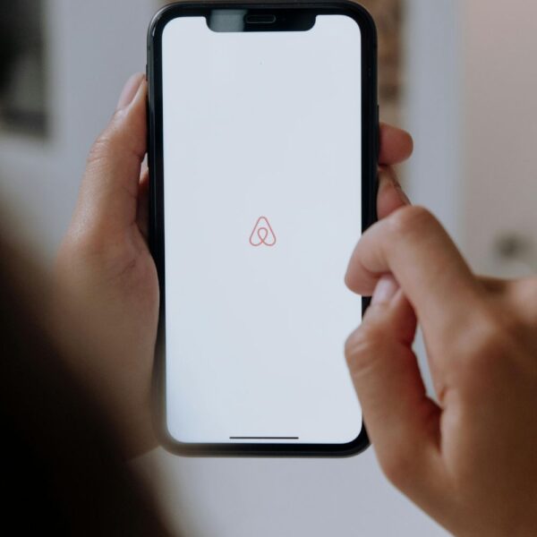 Image of woman's hands holding black cell phone, with Airbnb app opened