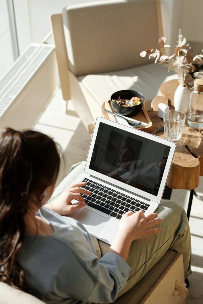 Image of living room with women holding a laptop in her lap looking at the screen