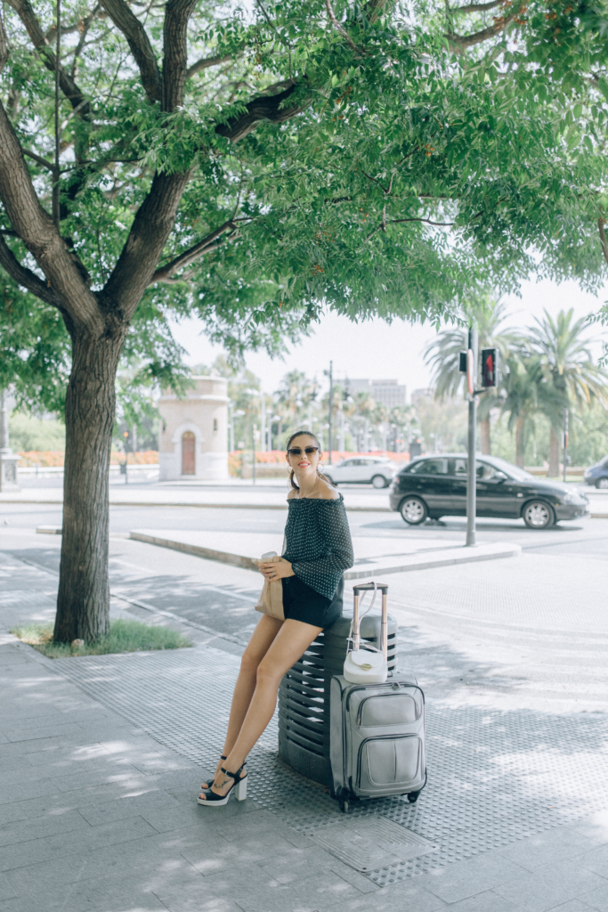 image of woman standing on street side with luggage