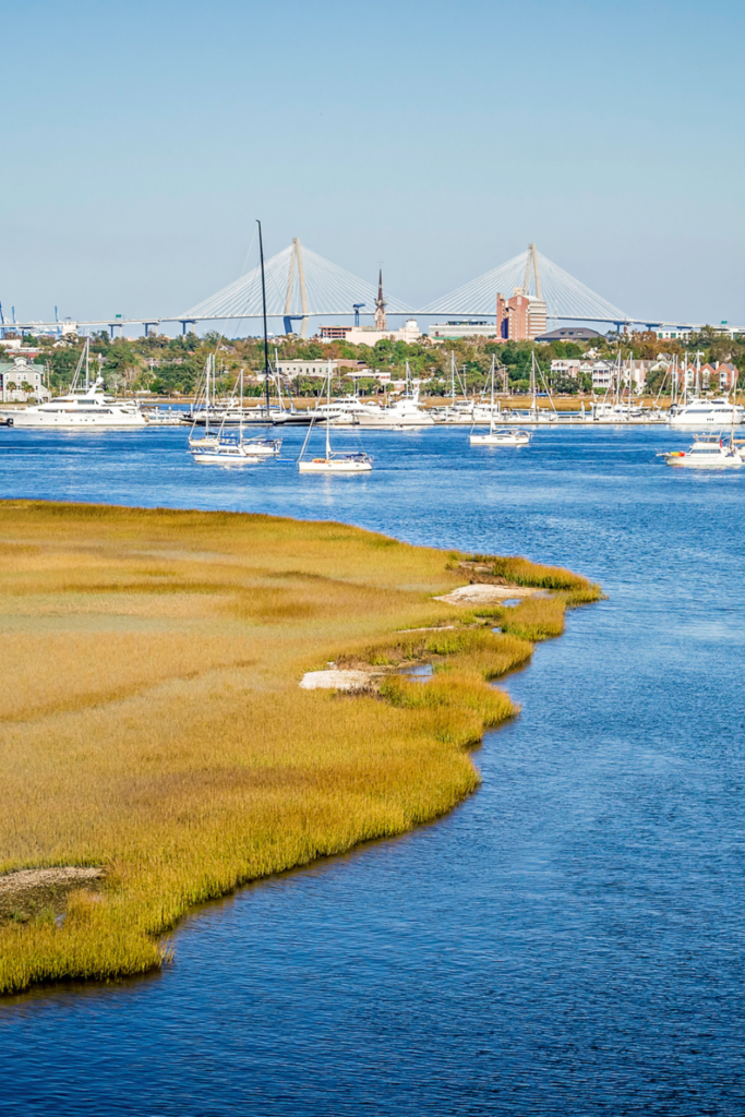 Aerial image of the Charleston Harbor area with ocean, land, boats, and bridge in the background