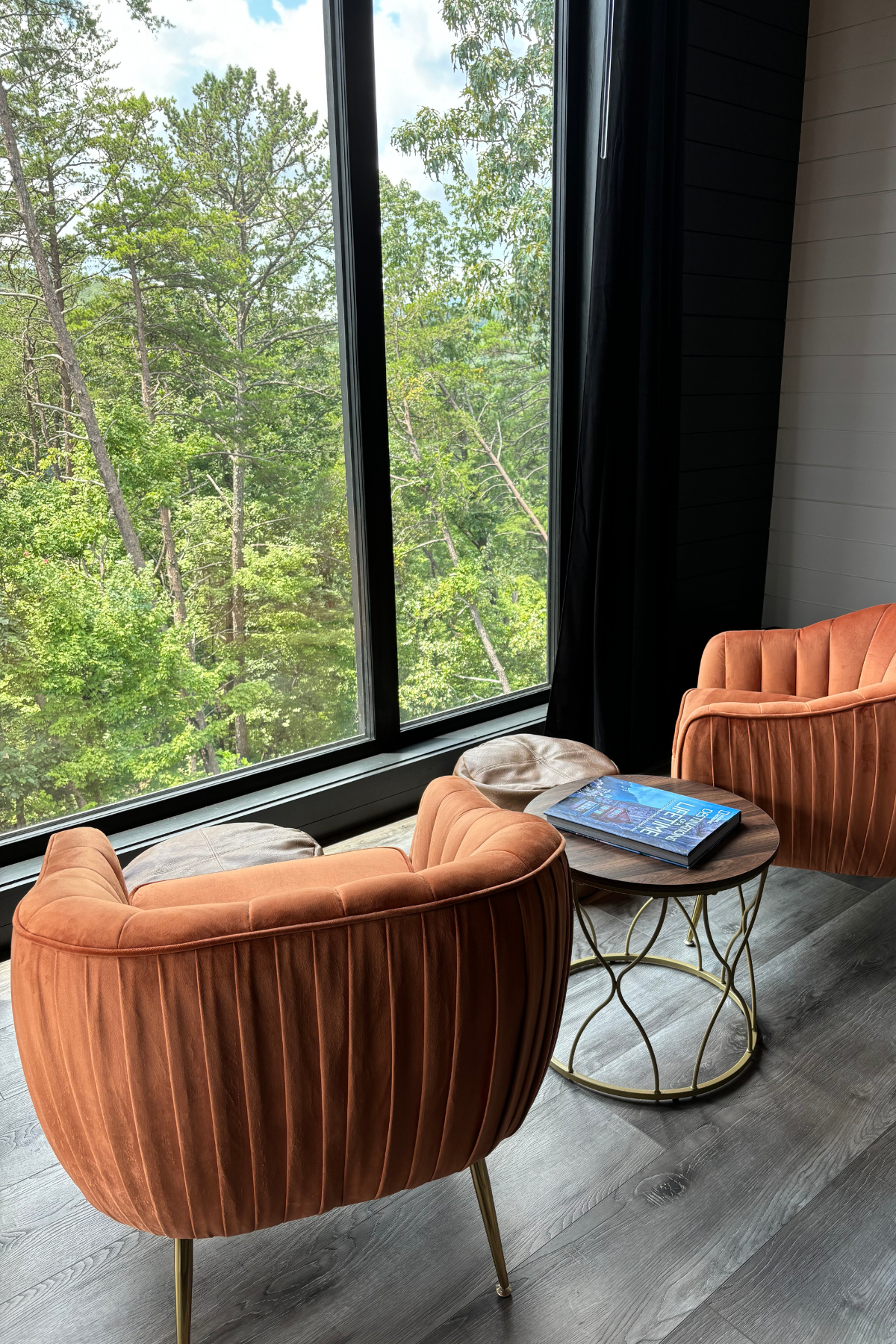 image of two orange arm chairs and coffee table overlooking a floor to ceiling window view of forest at Yonah Suite