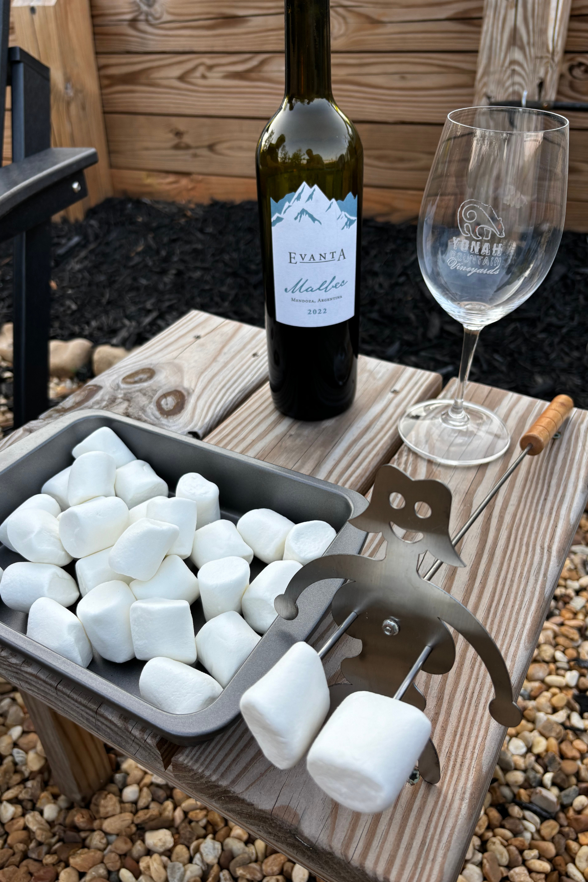 Image of marshmallows and a bottle of wine on a wooden table by a private fire pit during a Helen GA romantic weekend itinerary