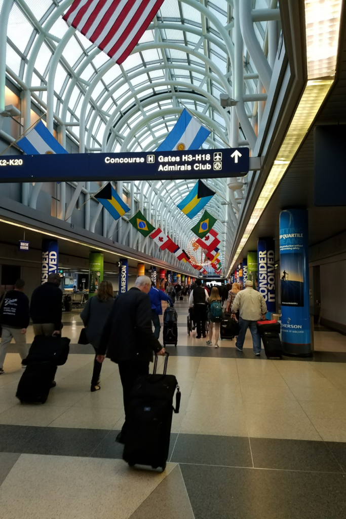 Image walking through airport with travelers, luggage, and backpacks