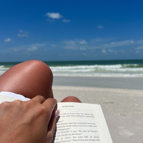 image of woman reading on a beach with ocean in background during road trips from Charleston SC