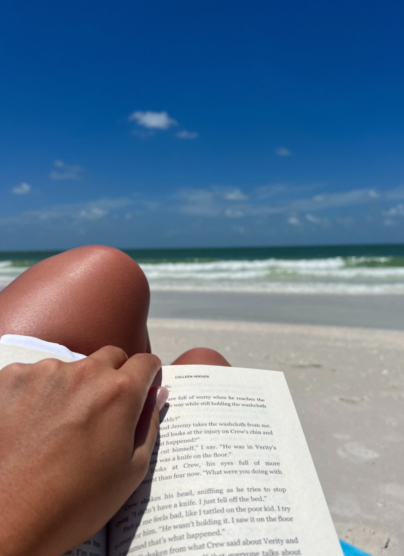 image of woman reading on a beach with ocean in background during road trips from Charleston SC