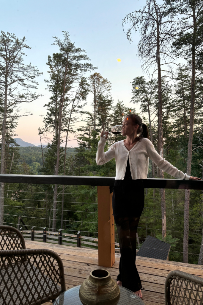 woman sipping a glass of red wine on the Yonah Suite balcony above helen ga