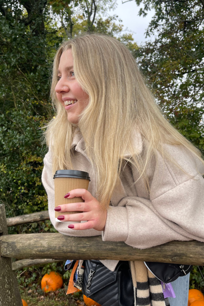 Image of blonde woman leaning on bridge with coffee in Hand doing fun activities in November in Atlanta