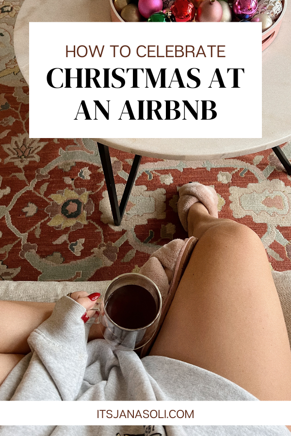 A first person point of view image looking down at mug on lab beside coffee table and bowl of Christmas decor. This is the cover image for the blog post 'How to Celebrate Christmas at an Airbnb'