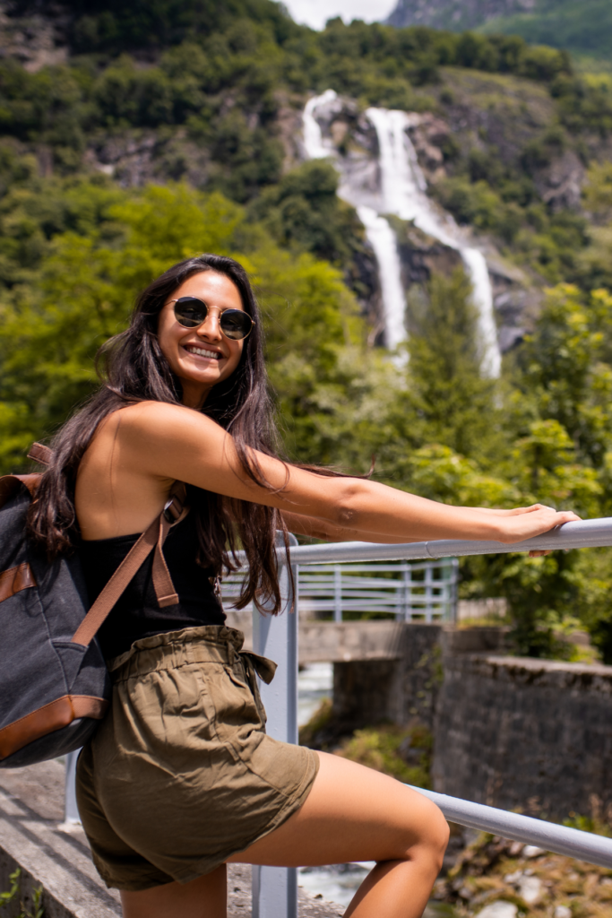 Image of woman on bridge smiling with waterfall in background