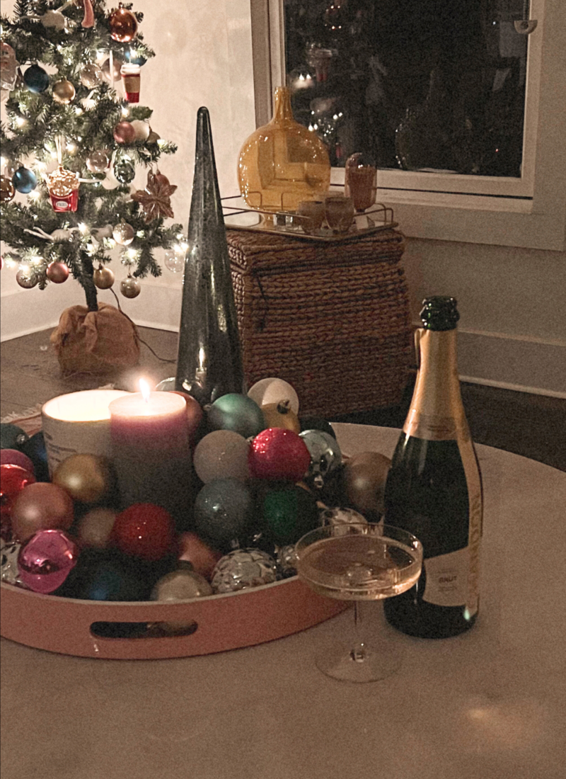 Image of coffee table topped with Christmas decor, bottle of champagne, and full champagne glass.