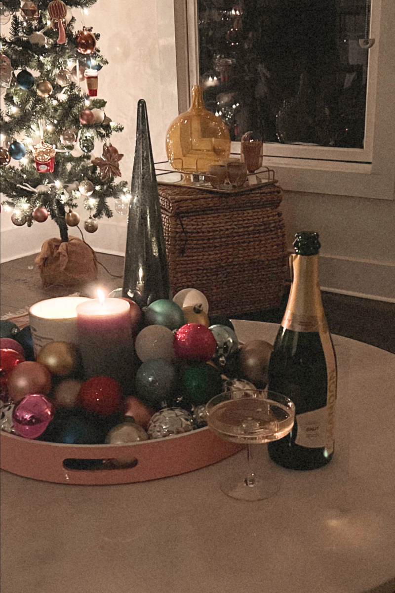 Image of coffee table topped with Christmas decor, bottle of champagne, and full champagne glass.