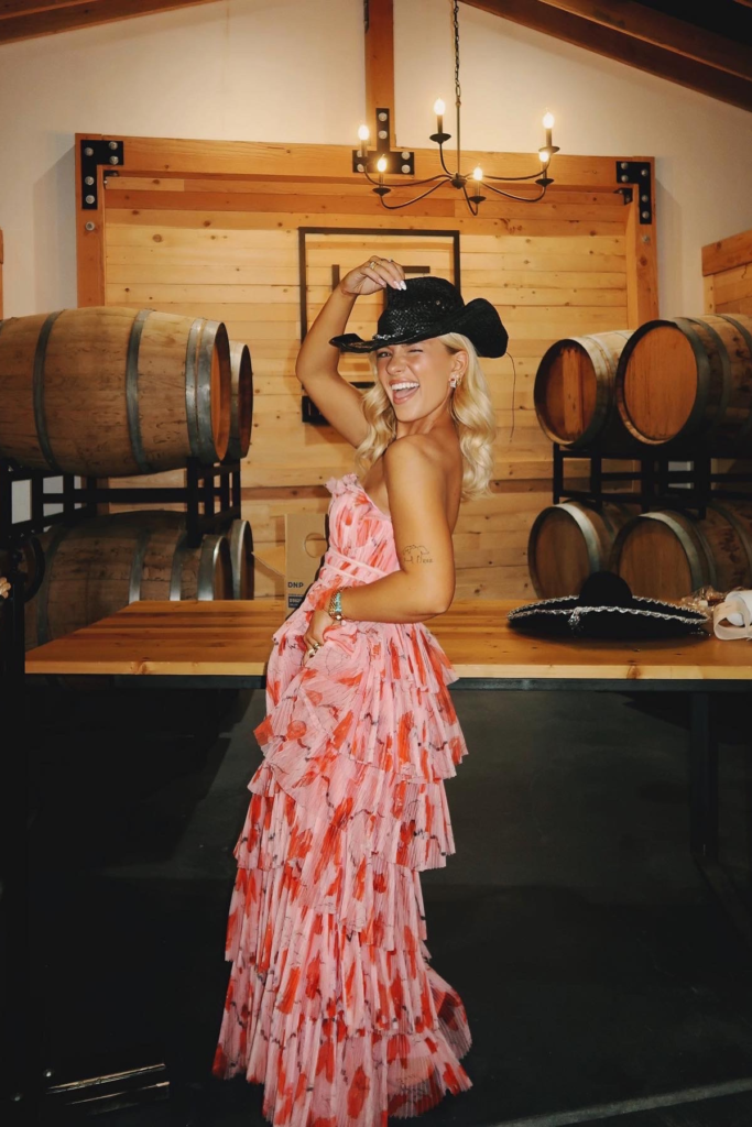 Image of woman in floral pink dress and black cowboy hat smiling. Image of woman in bright yellow floral dress for Image of red dress and wooden half circle purse on woman sitting on white chair. Part of the rent the runway honest review for wedding guest blog post.