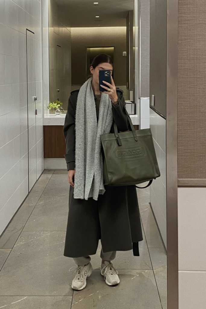 image of woman taking a selfie in airport bathroom mirror with oversized carry on luggage