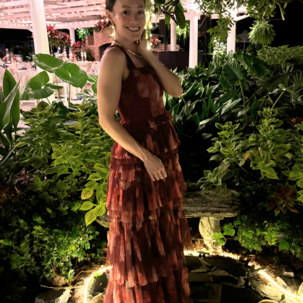 Image of woman standing in red formal dress with garden in background