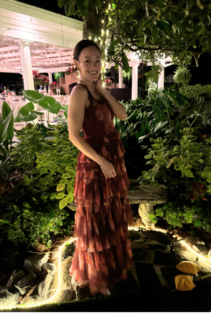 Image of woman standing in red formal dress with garden in background