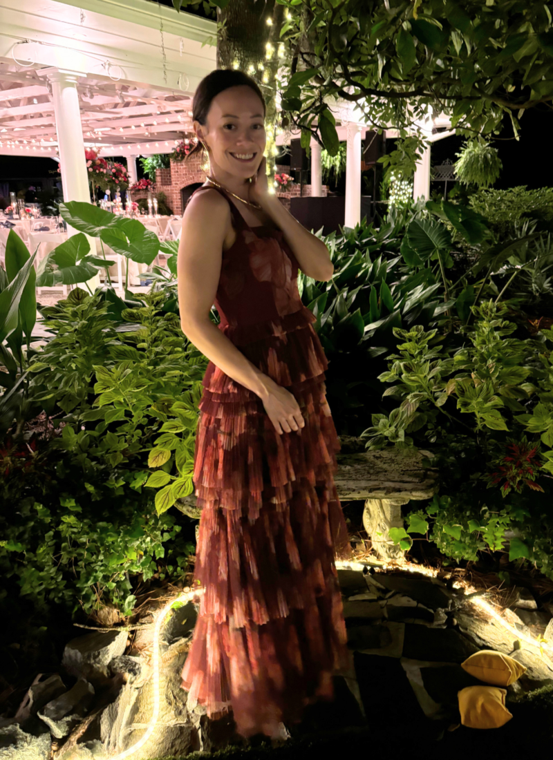 Image of woman standing in red formal dress with garden in background