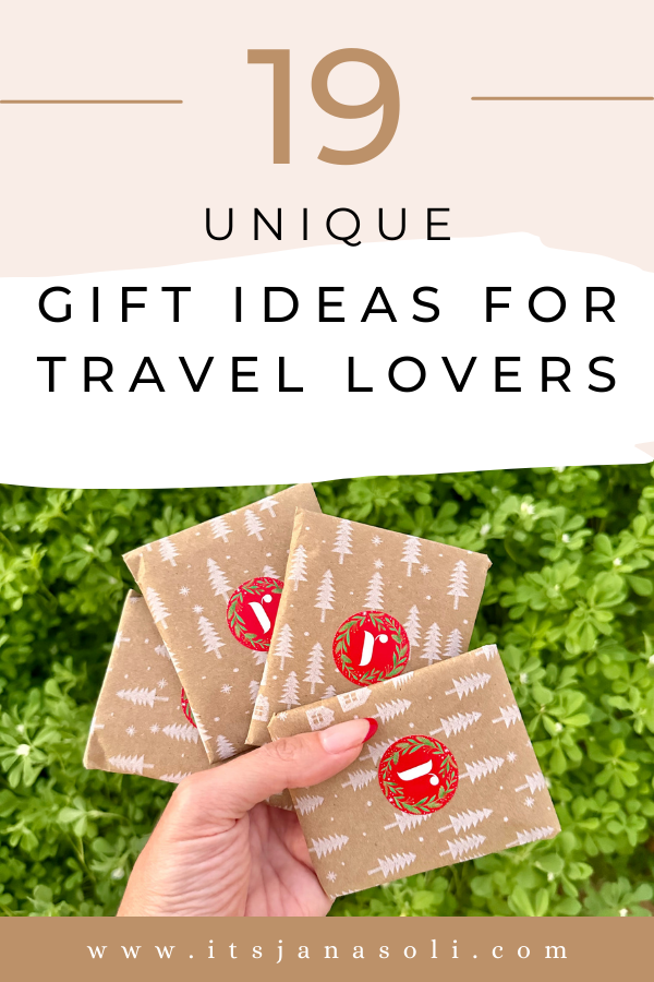 Image of woman's hand holding gift wrapped airplane gift cards. Writing on image says "19 Unique Gift Ideas for Travel Lovers".