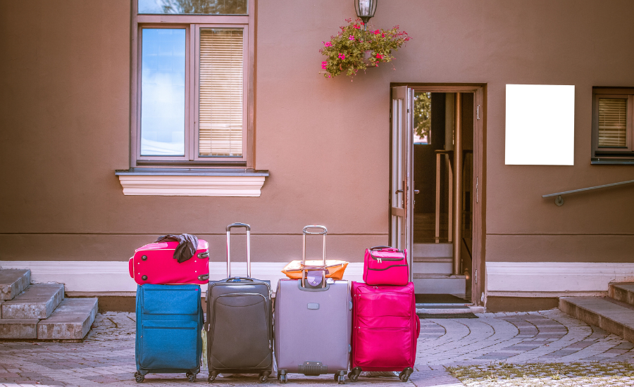 Four colorful suit cases lined up outside door of Airbnb.