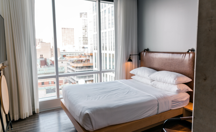 Airbnb bedroom with floor to ceiling windows looking out to the city.