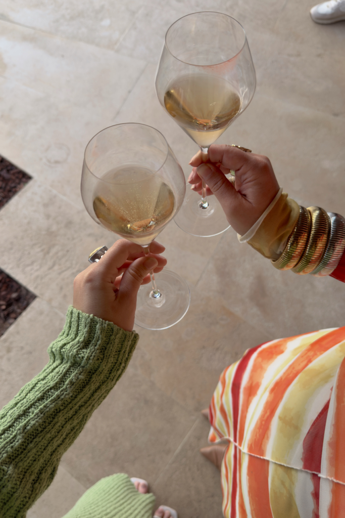 Top down image of two women in dresses holding glasses of white wine at beer festival in Atlanta in January.