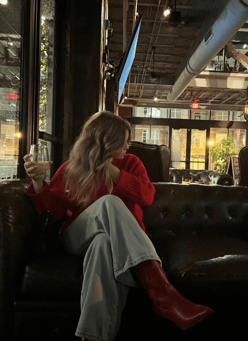 Woman in red sweater and boots sitting in restaurant in Atlanta Georgia.